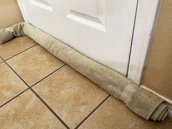 blocking weather draft with rolled up towel at bottom of door